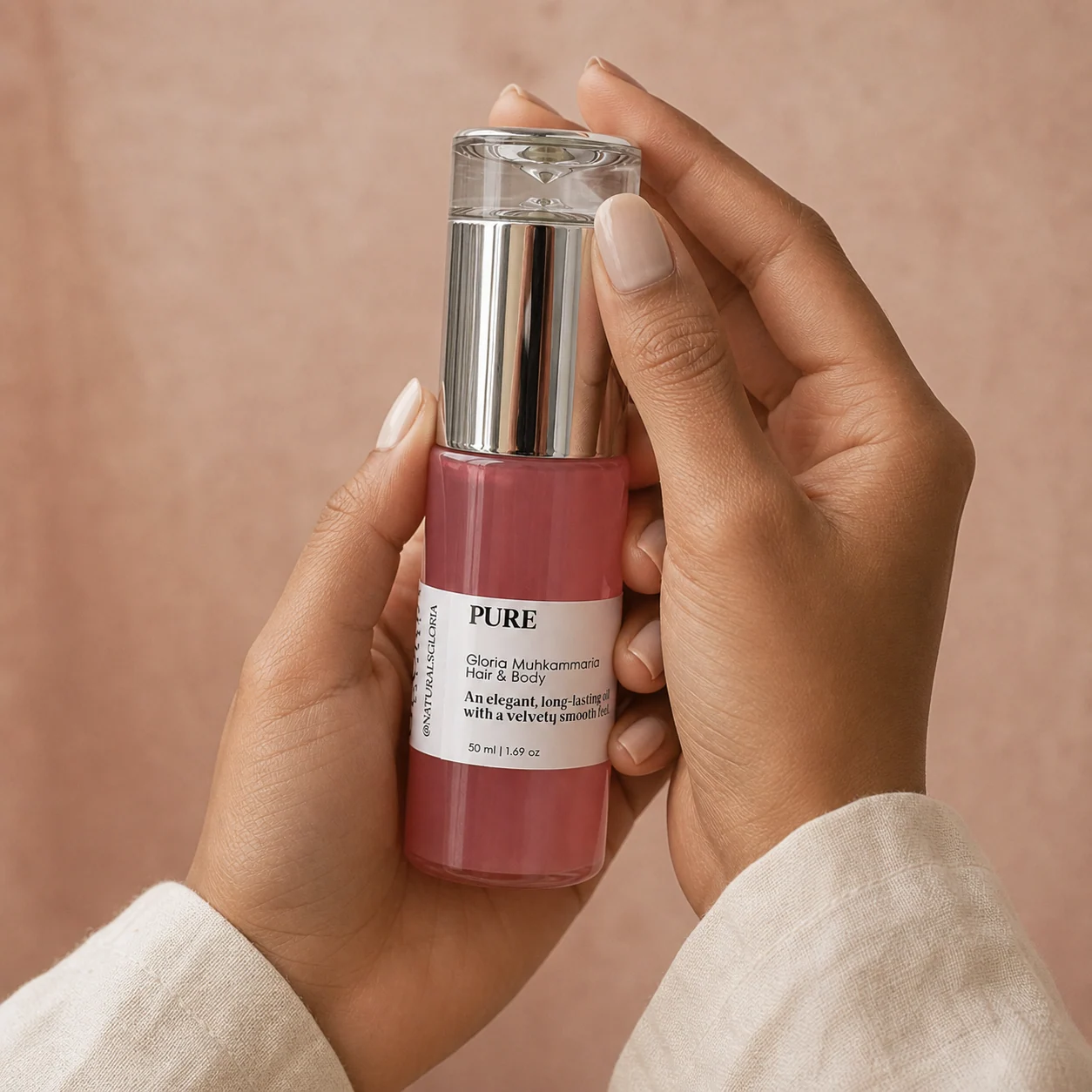 Two hands holding a bottle of Gloria Muhkammaria oil